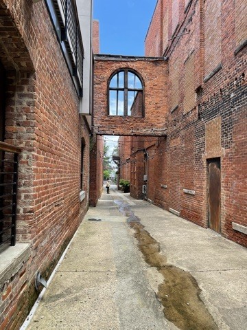 A narrow brick passage framed by arched windows and overhead walkways