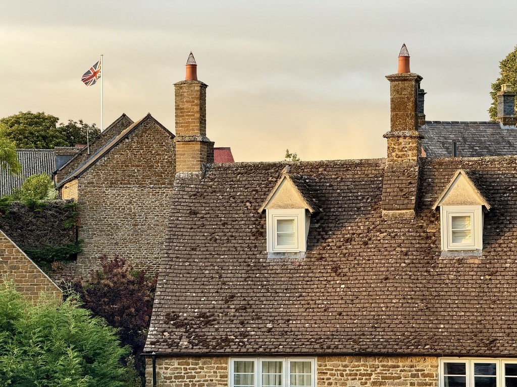 Stone roofs and tall chimneys beneath a warm sky