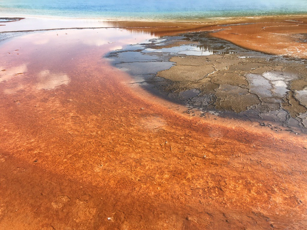 Orange mineral terraces surrounding a steaming blue pool