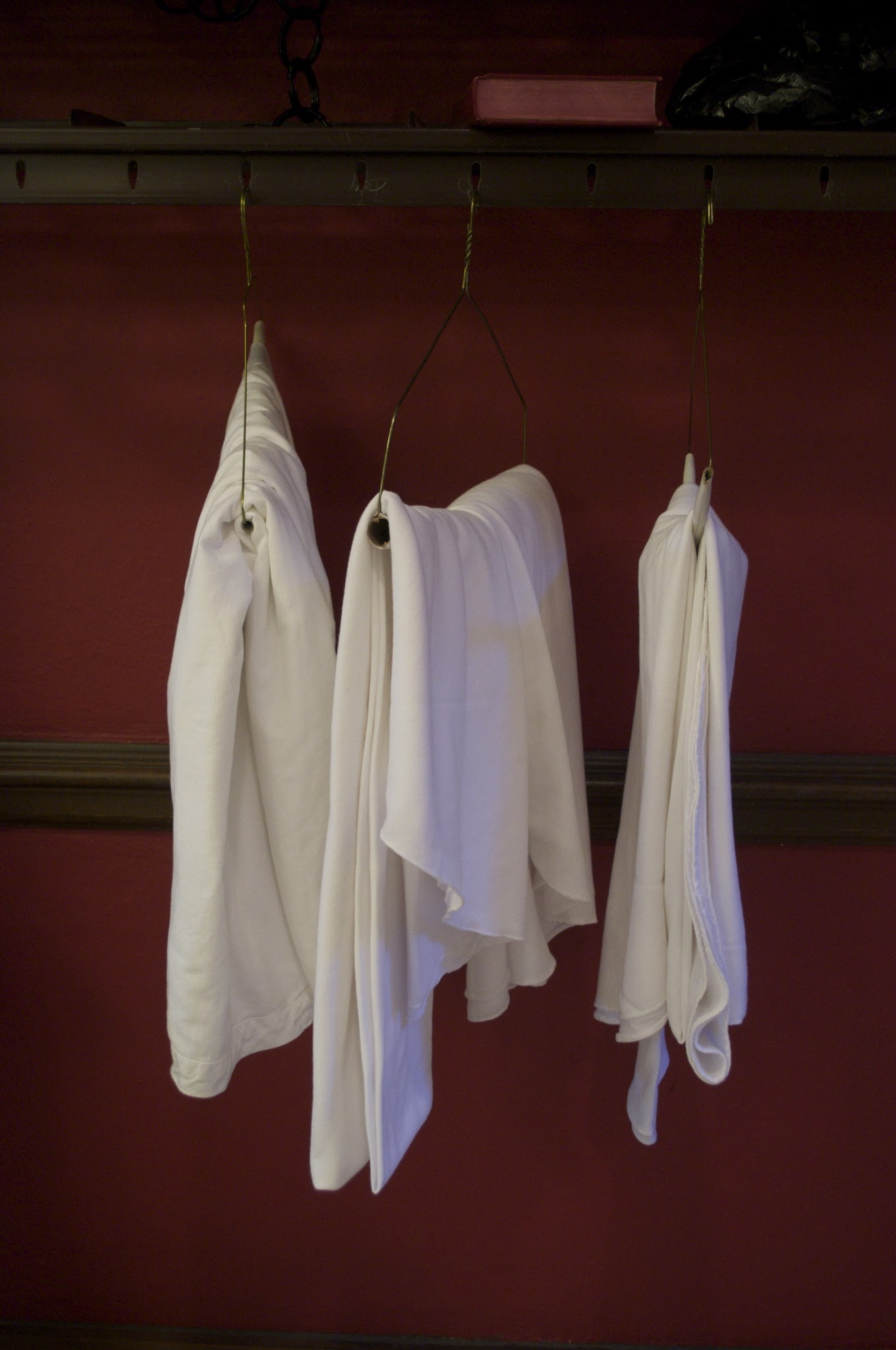 White garments hanging against a deep red wall