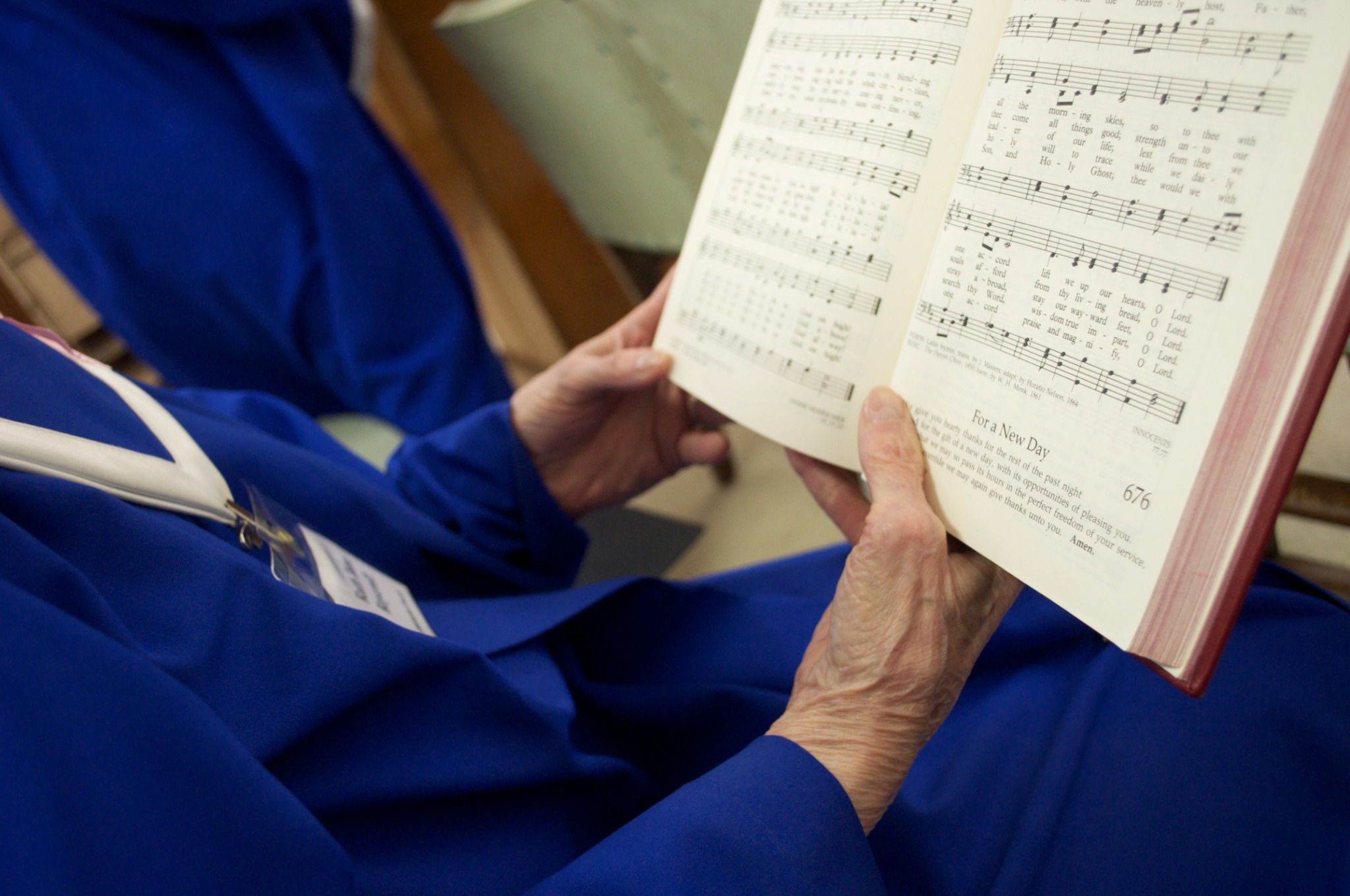 A choir member in a blue robe holding an open hymnal
