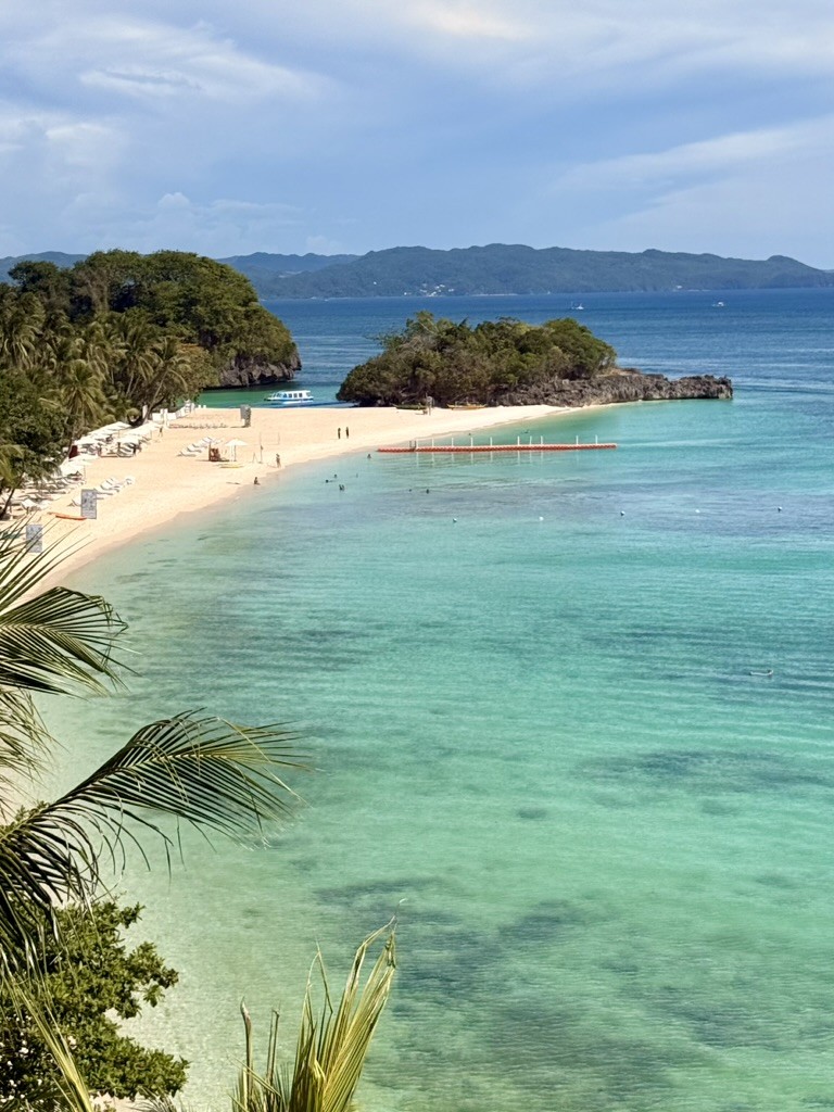 A turquoise bay with a sandy beach and green islands